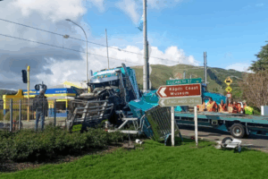 Crash scene showing a damaged blue truck after a collision with a freight train near Waikanae Railway Station, with emergency workers on site and road signs pointing to Elizabeth Street and Kāpiti Coast Museum.