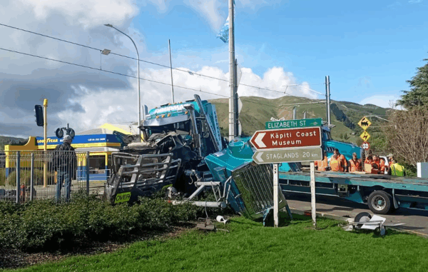 Train Truck Crash scene showing a damaged blue truck after a collision with a freight train near Waikanae Railway Station, with emergency workers on site and road signs pointing to Elizabeth Street and Kāpiti Coast Museum.
